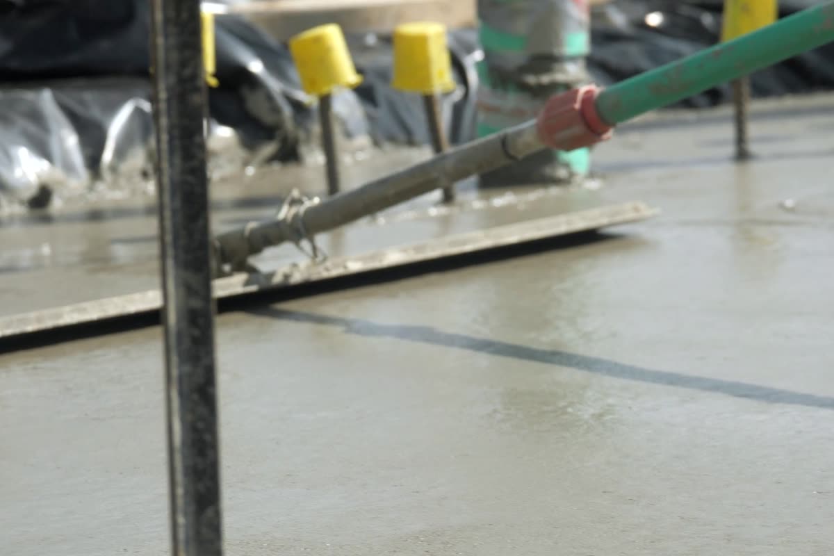 Screed bar being pulled across a freshly poured concrete slab
